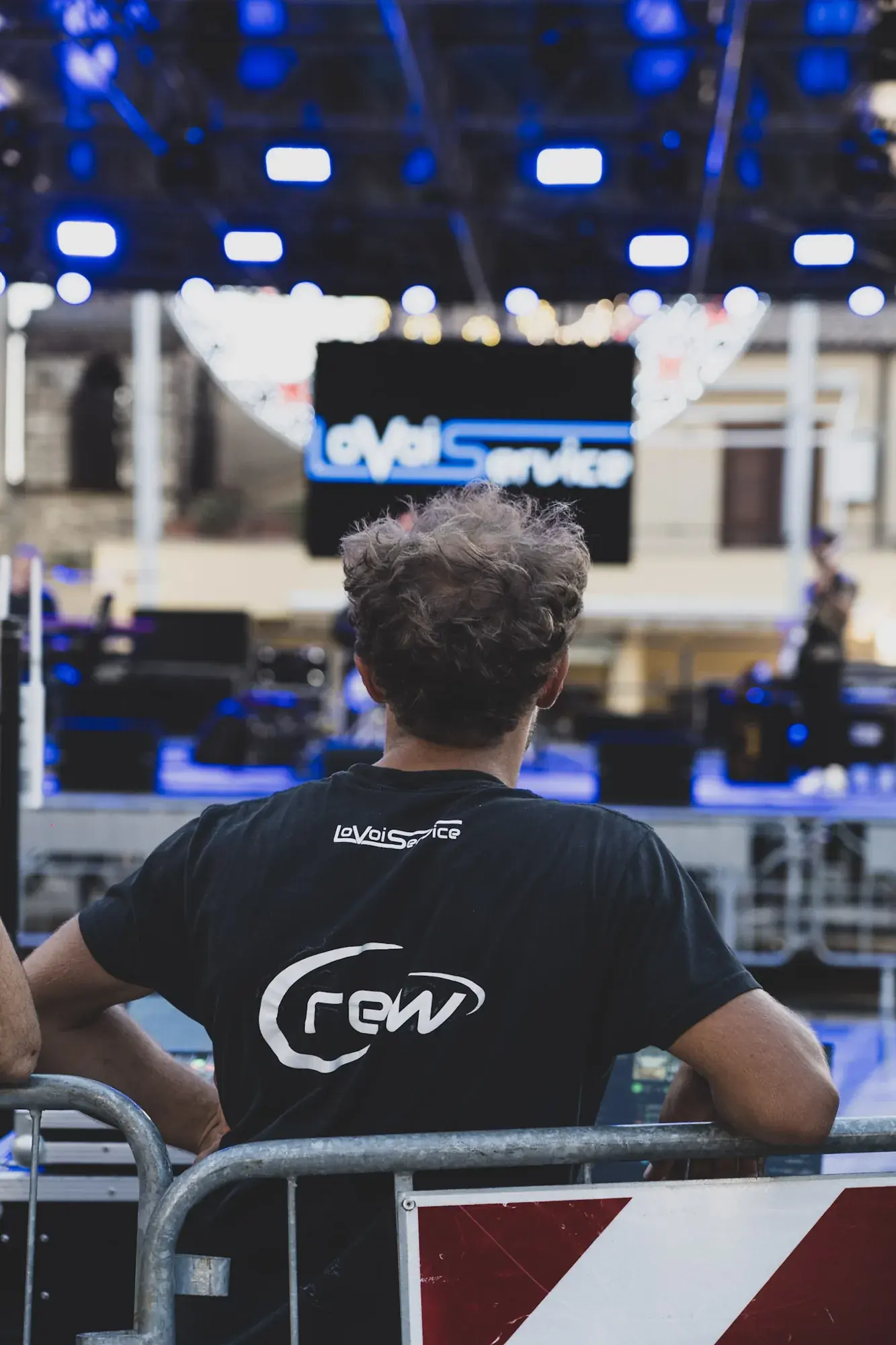 Tecnico della crew davanti al palco con il logo Lo Voi Service sul ledwall